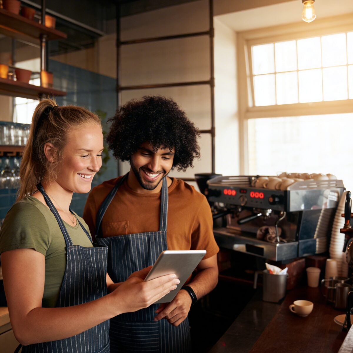 Baristas using tablet POS system to manage orders in a busy coffee shop