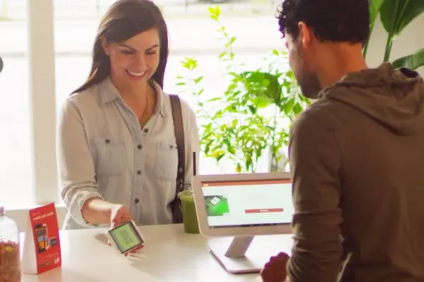 Customer presenting a digital loyalty or gift card at a restaurant checkout counter
